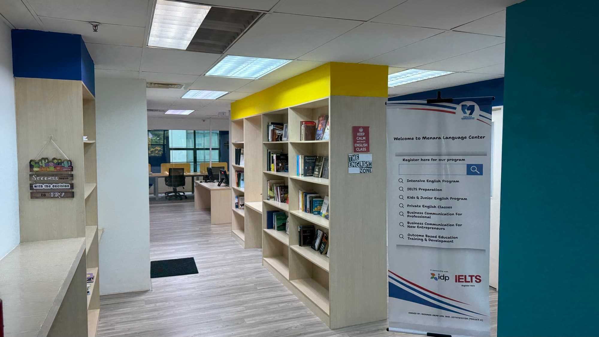 الممر الرئيسي داخل معهد MLC مع لوحة الترحيب ورفوف كتب اللغة الإنجليزية